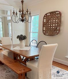 a dining room table with two chairs and a bench in front of the chandelier