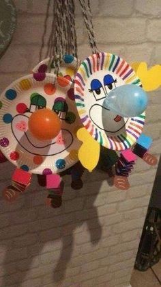 a paper plate with a clown face hanging from it's side on a chain