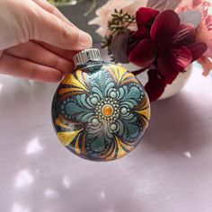 a hand holding a flask with flowers in the background