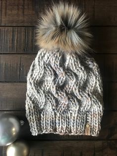 a knitted hat with two pom - poms sitting on top of it