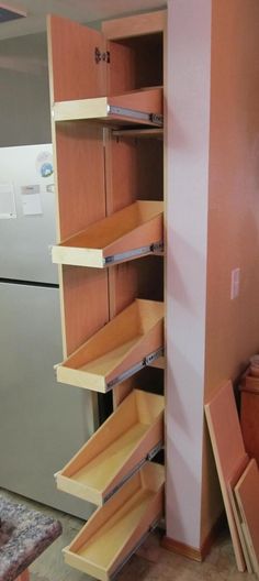 an open cabinet door in a kitchen next to a refrigerator