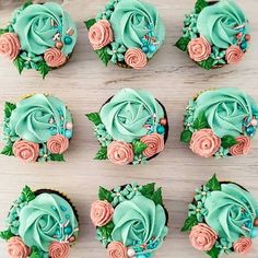 cupcakes decorated with blue frosting and pink roses are arranged on a table