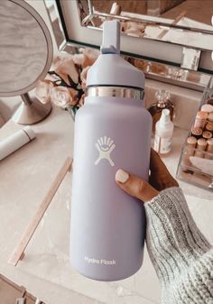 a person holding a purple water bottle with the word hydro flask printed on it