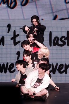 a group of young men standing on top of each other in front of a sign