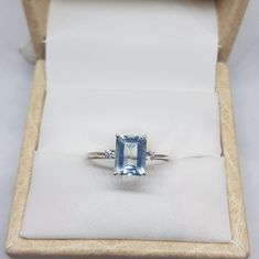 an engagement ring with a blue topazte surrounded by two diamonds in a box