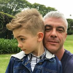 an older man holding a young boy who is wearing a denim jacket and looking at the camera