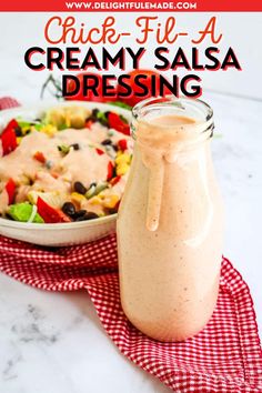 a glass jar filled with creamy salsa dressing next to a red and white checkered napkin