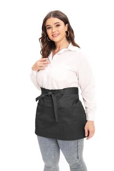 a woman wearing an apron and white shirt with her hands on her hips, posing for the