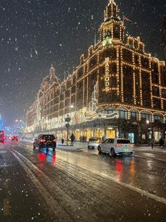 cars driving down the road in front of a building with christmas lights on it's sides