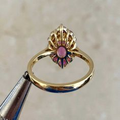 This gorgeous ring features a 1.92 carat oval-cut pink tourmaline ring that is set in prongs. Flanking either side of the stone are two oval-cut diamonds weighing approximately 0.11 carats. Additional prong-set rubies and spinel form a halo around the center stone. The total weight of the spinel is approximately 0.11 carats and the total weight of the rubies is approximately 0.25 carats. This ring is handcrafted in 18k yellow gold.
The measurements of the center tourmaline are 9.34mm x 6.53mm x Oval Ruby Ring With Diamond, Luxury Pink Oval Cluster Ring, Timeless Oval Ruby Ring With Diamonds, Oval Ruby Ring With Diamond Center Stone, Exquisite Pink Sapphire Gemstone Rings, Exquisite Oval Ruby Ring, Exquisite Oval Ruby Ring With Center Stone, Formal Pink Marquise Diamond Ring, Exquisite Pink Sapphire Ring With Prong Setting