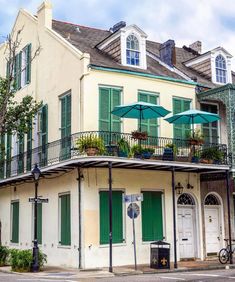 an old building with green shutters and umbrellas on the balconies