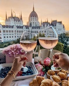 two people toasting glasses of wine at a table with pastries