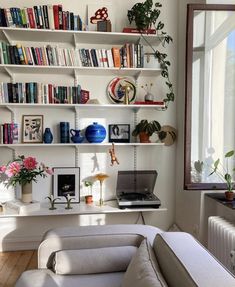 a laptop computer sitting on top of a white desk next to a book shelf filled with books