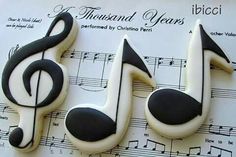 music themed cookies with black and white icing on sheet music notes are in the background