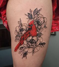 a red bird sitting on top of a flowery branch with leaves and flowers around it