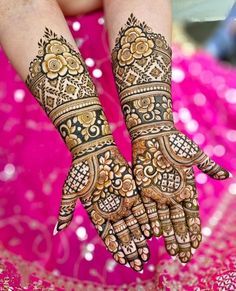 two hands with henna tattoos on them