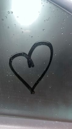 a heart drawn on the side of a car window with water droplets all over it