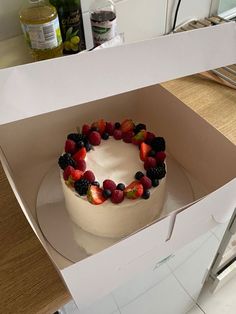 a white cake with fruit on top in a box