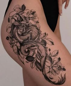 a woman's thigh with flowers and a dragon tattoo on it