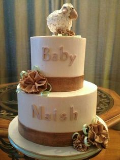 a three tiered cake decorated with flowers and a lamb on top that says baby naish