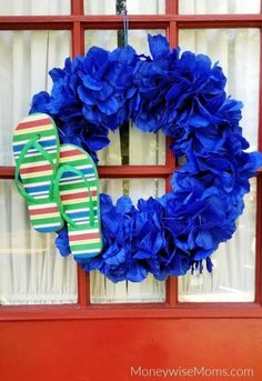 a blue wreath with flip flops hanging on the side of a red front door