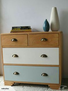 a white and blue chest of drawers next to a vase on top of a rug