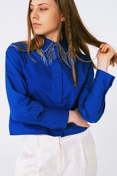 Get ready to dazzle at your next social gathering with our Shirt With Fringe Strass Collar in Blue. Crafted from 100% Cotton, this shirt offers both style and comfort. Designed to run true to size, the model showcasing this shirt is 5'9" with a 32-24-35 figure, wearing a size S. With its polo collar and long sleeves, this standard fit shirt provides a flattering silhouette. The highlight of this party-ready shirt is the Fringe Strass detail on the collar, adding a unique sparkle to the premium p