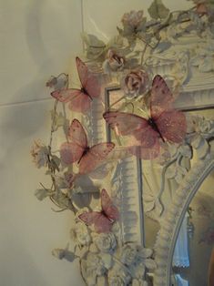 a mirror with some pink butterflies hanging from it's side and on the wall