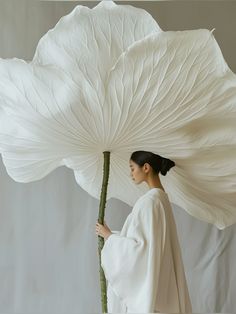 a woman holding a large white flower in her hands