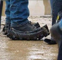 two people standing next to each other in the rain with their shoes on and one person wearing blue jeans