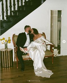 a bride and groom kissing in front of a staircase