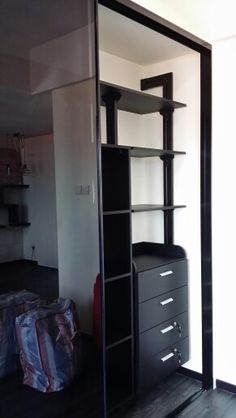 an empty room with black shelves and drawers on the floor, in front of a mirror