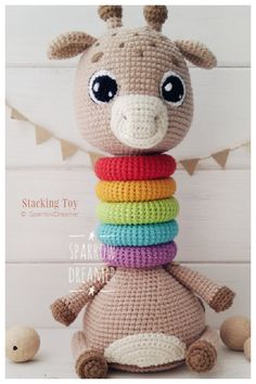 a crocheted giraffe sitting on top of a stack of multicolored blocks