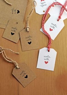 some tags are hanging from twine on a wooden table with red and white twine