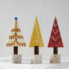 three small christmas trees sitting on top of each other in front of a white wall