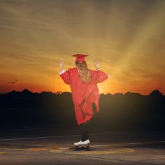 a woman in a red graduation gown riding a skateboard