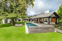 a house with a pool in the middle of it and grass around it, surrounded by trees