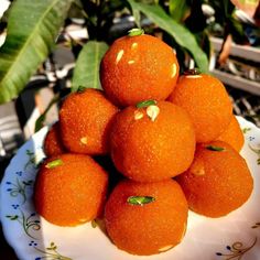 a white plate topped with oranges on top of a table next to green leaves