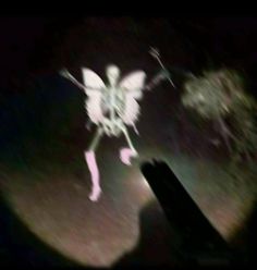 a blurry image of a person holding a cell phone in the dark with an angel on it