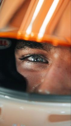 a close up of a person's face with an orange helmet over their head