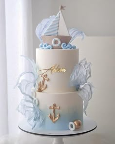 a three tiered cake with an anchor, sailboat and seagulls on top