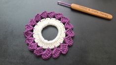 a crocheted circle next to a knitting needle on top of a black surface