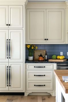 a kitchen with white cabinets and blue backsplash