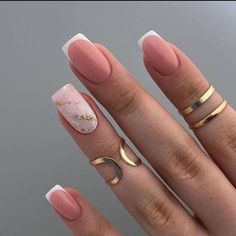 a woman's hand with pink and white manicured nails, gold rings and an oval