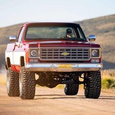 a red pickup truck driving down a dirt road