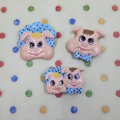 three pink and blue pigs with polka dots on a white tablecloth next to colorful circles