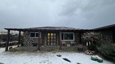 a small stone house covered in snow on a cloudy day