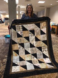 a woman is holding up a quilt made from old newspaper pages in an office building