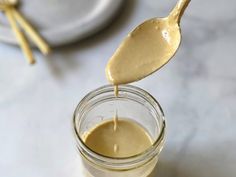 a spoon full of peanut butter being poured into a jar