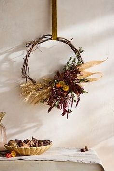 a table topped with a bowl of food next to a vase filled with dried flowers